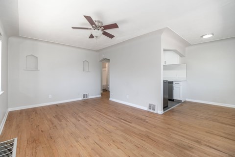 A room with a ceiling fan and wooden flooring.