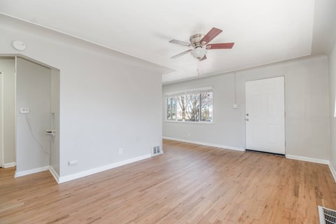 A room with a ceiling fan and wooden flooring.