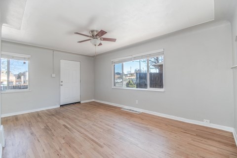 A room with a ceiling fan and wooden flooring.