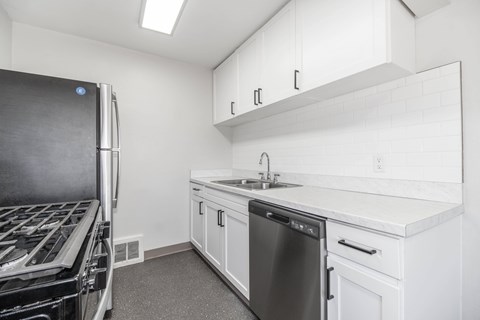 A modern kitchen with white cabinets and a stainless steel dishwasher.