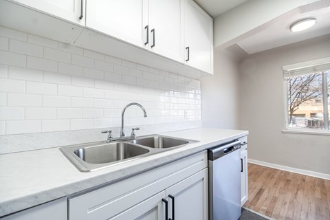 A kitchen with a white tile backsplash and white cabinets.