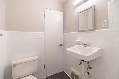 A white bathroom with a toilet, sink, and mirror.