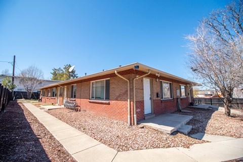 A small brick house with a white door and windows.