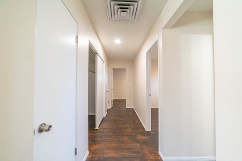 A long hallway with white walls and a wooden floor.