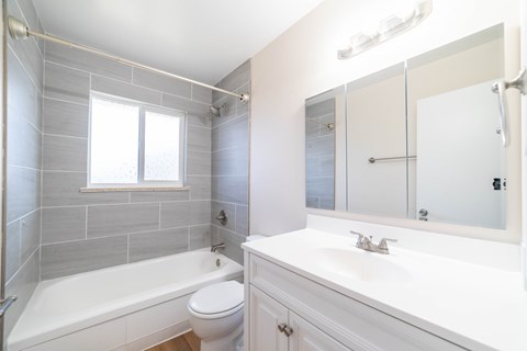 A white bathroom with a tub, toilet, and sink.