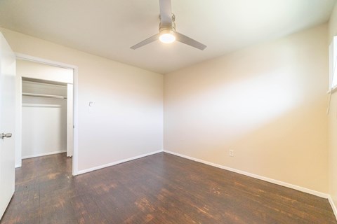 A room with a ceiling fan and wooden flooring.