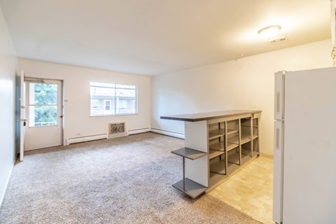 A room with a window, a table, and a refrigerator.