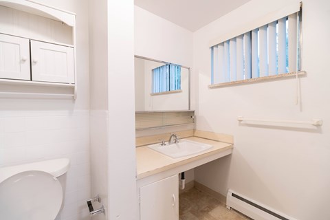 A white bathroom with a toilet, sink, and window.