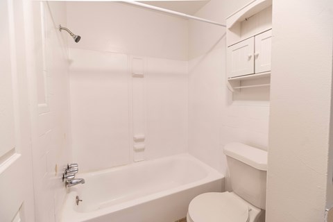 A white bathroom with a tub, toilet and sink.