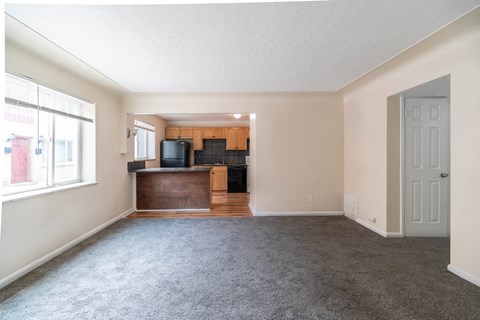 A living room with a grey carpet and a wooden entertainment center.