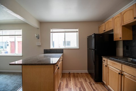 A kitchen with wooden cabinets and a black refrigerator.