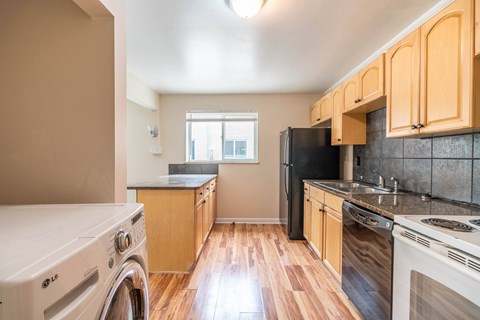 A kitchen with wooden cabinets and a black refrigerator.