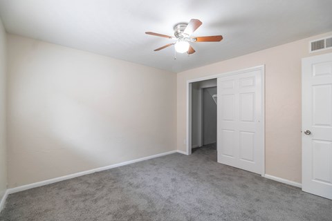 A room with a ceiling fan and carpeted floor.