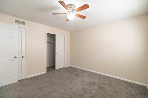A room with a ceiling fan and carpeted floor.