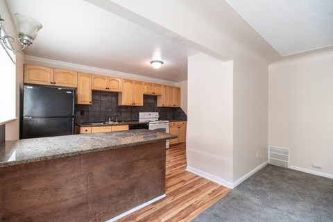 A kitchen with wooden cabinets and a black fridge.