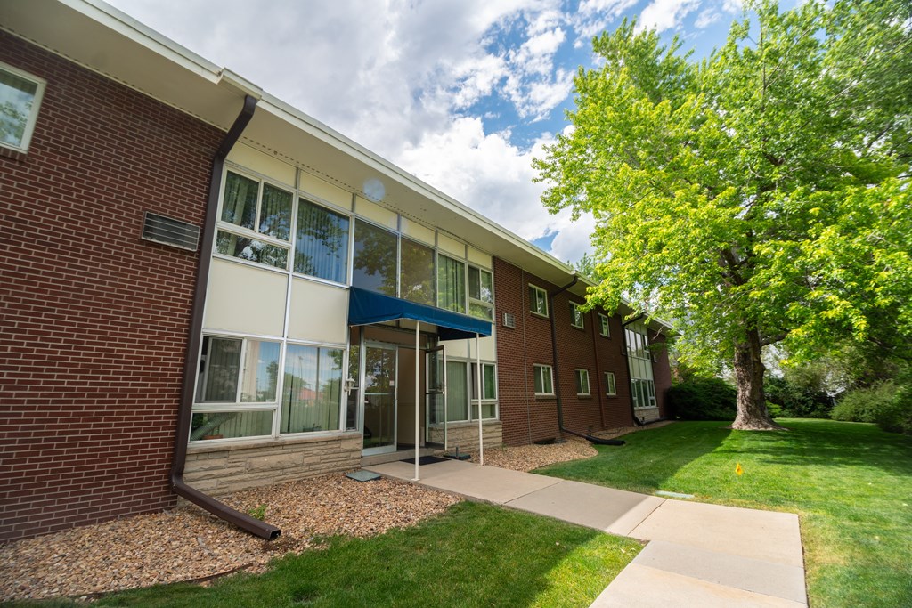 A building with a blue awning and a tree in front of it.