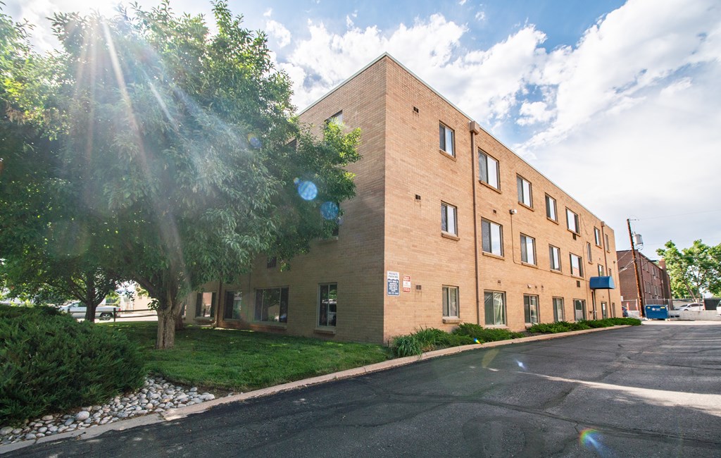 A sunny day at a modern brick building with a parking lot in front.