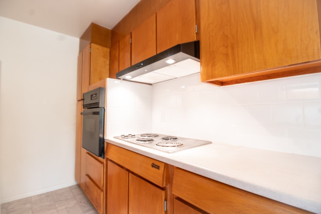 A kitchen with wooden cabinets and a black oven.