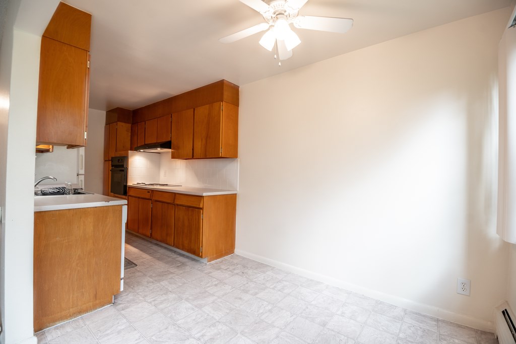 A kitchen with wooden cabinets and a ceiling fan.