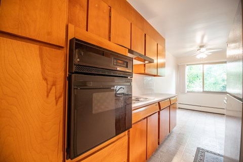 A modern kitchen with wooden cabinets and a black oven.