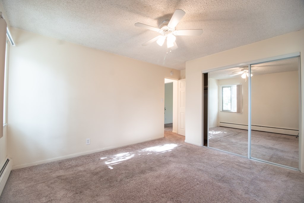 A room with a ceiling fan and a mirror on the wall.
