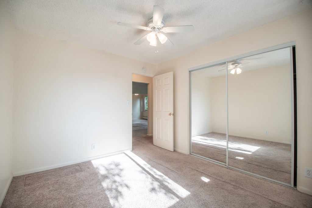 A room with a ceiling fan and a large mirror on the wall.