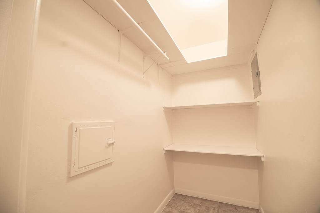 A white wall with a white shelf and a white box on it.