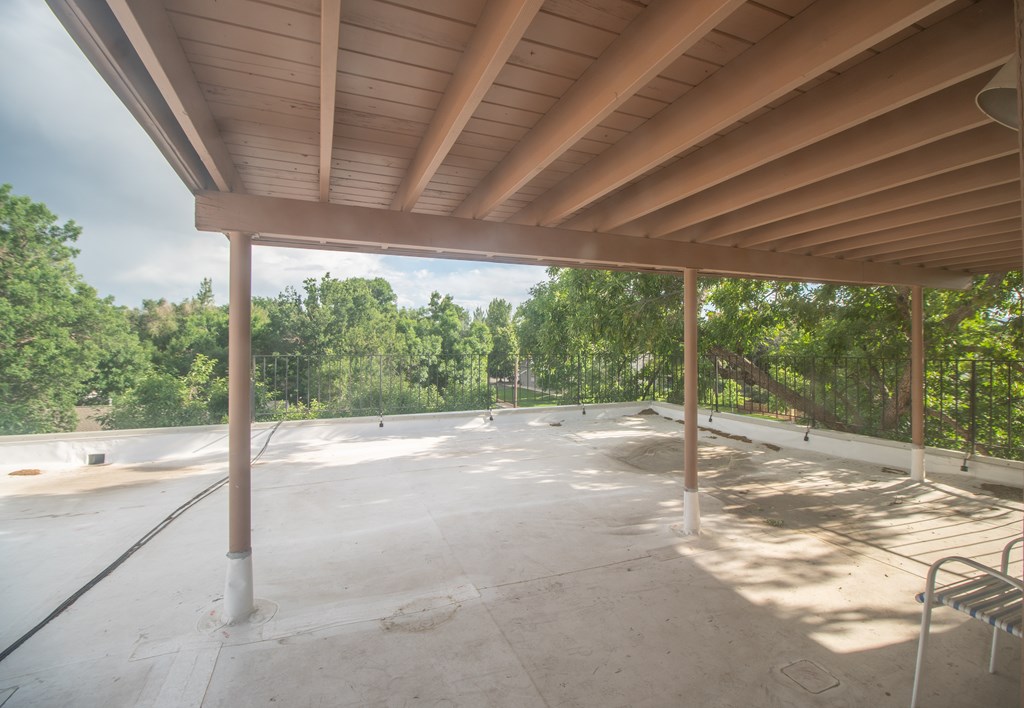 A covered patio area with a wooden ceiling and concrete floor.