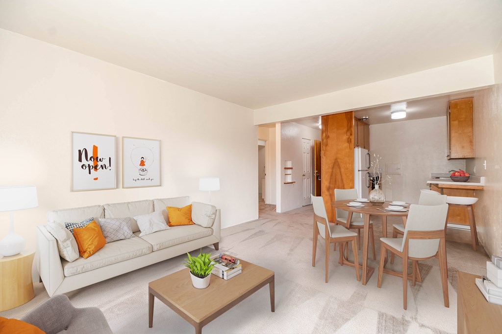 A living room with a couch, coffee table, and a dining table with chairs.