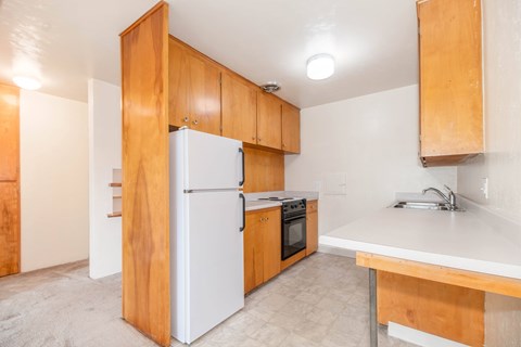 A kitchen with a white refrigerator and wooden cabinets.