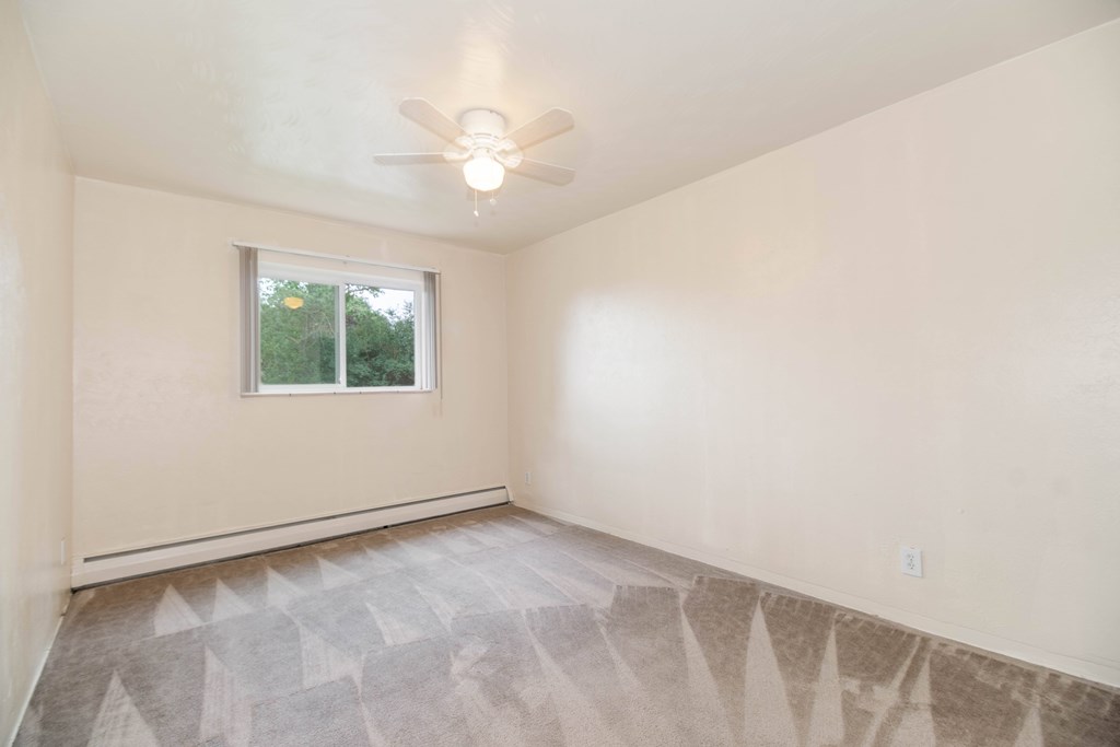 A room with a ceiling fan and a window.