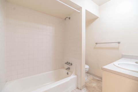 A white bathroom with a tub, toilet, and sink.
