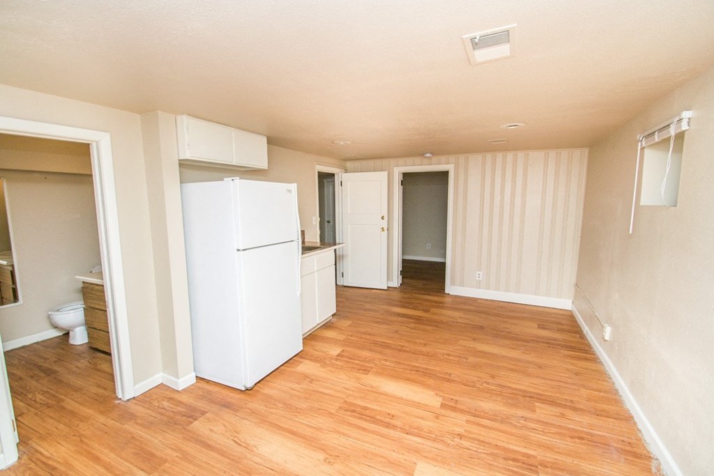 a kitchen with a white refrigerator and a wooden floor