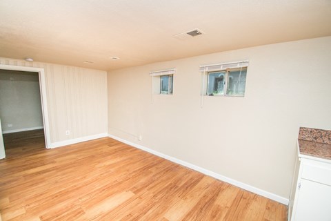 an empty living room with wood floors and white walls