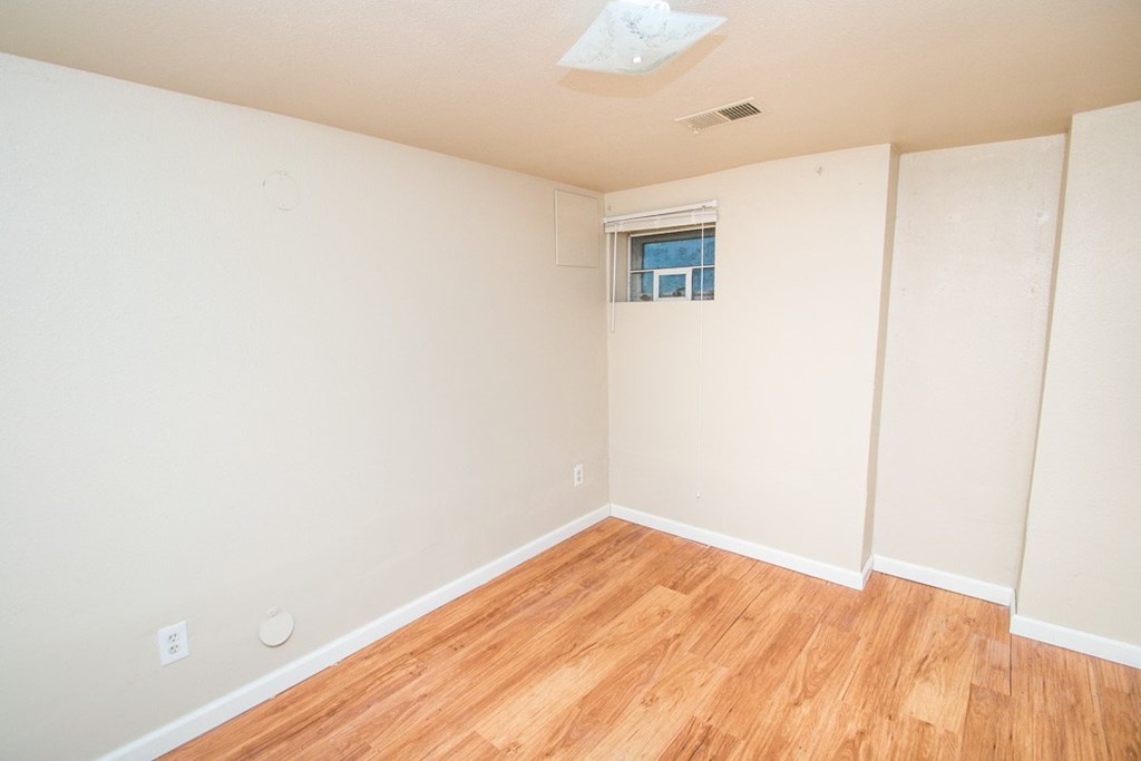 an empty room with a wood floor and white walls
