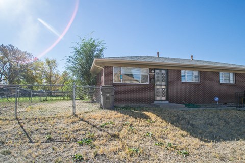 A house with a fence and a tree in front of it.