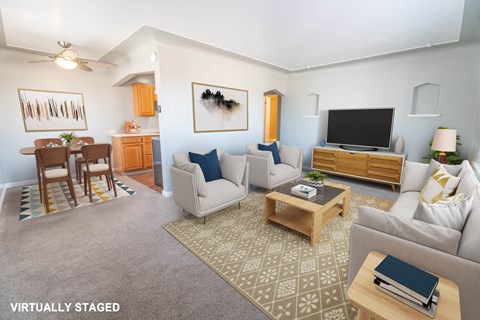 A living room with a grey couch, a coffee table, a television, and a dining table with chairs.
