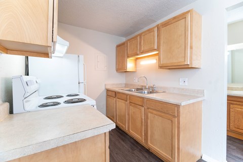 A kitchen with wooden cabinets and a white stove top oven.