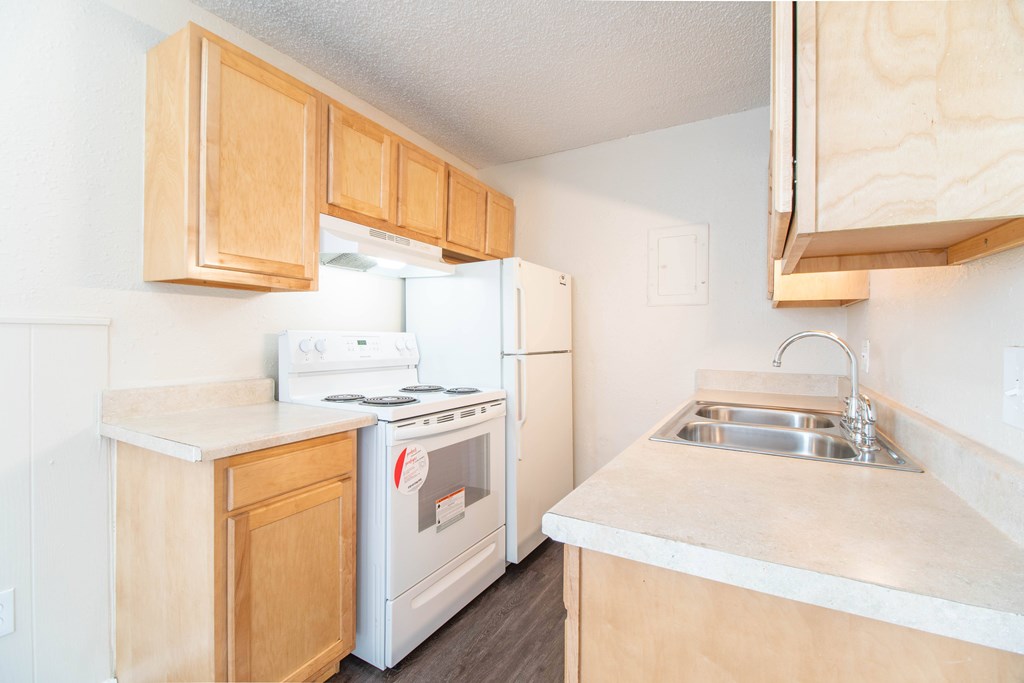 A kitchen with a white stove and a white refrigerator.