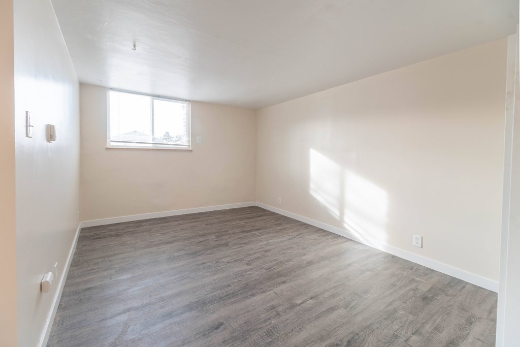 A room with a window and wooden flooring.