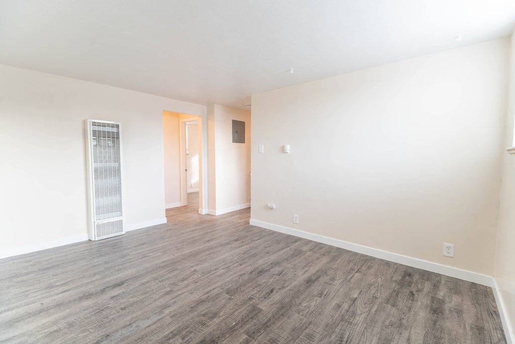 A room with a wooden floor and a door leading to another room.
