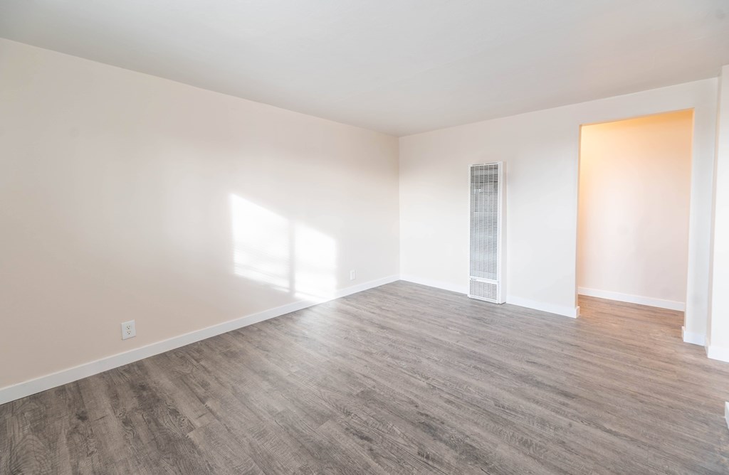 A room with wooden flooring and white walls.