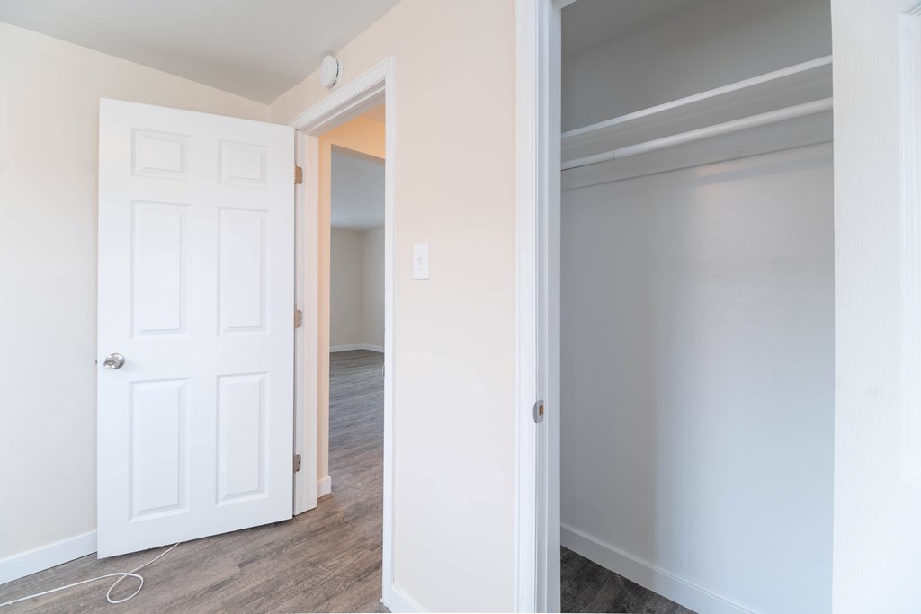 A white door is open to a room with a wooden floor.