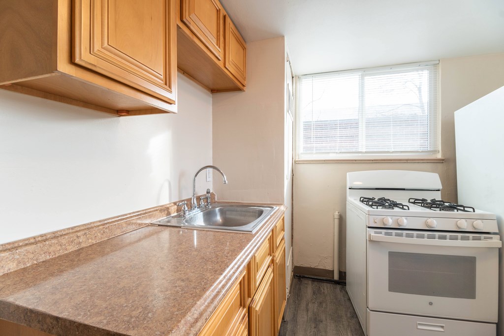 A kitchen with a white stove and wooden cabinets.