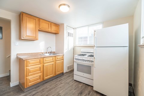 A kitchen with wooden cabinets and a white fridge.