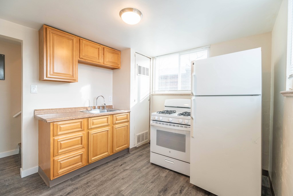 A kitchen with wooden cabinets and a white fridge.