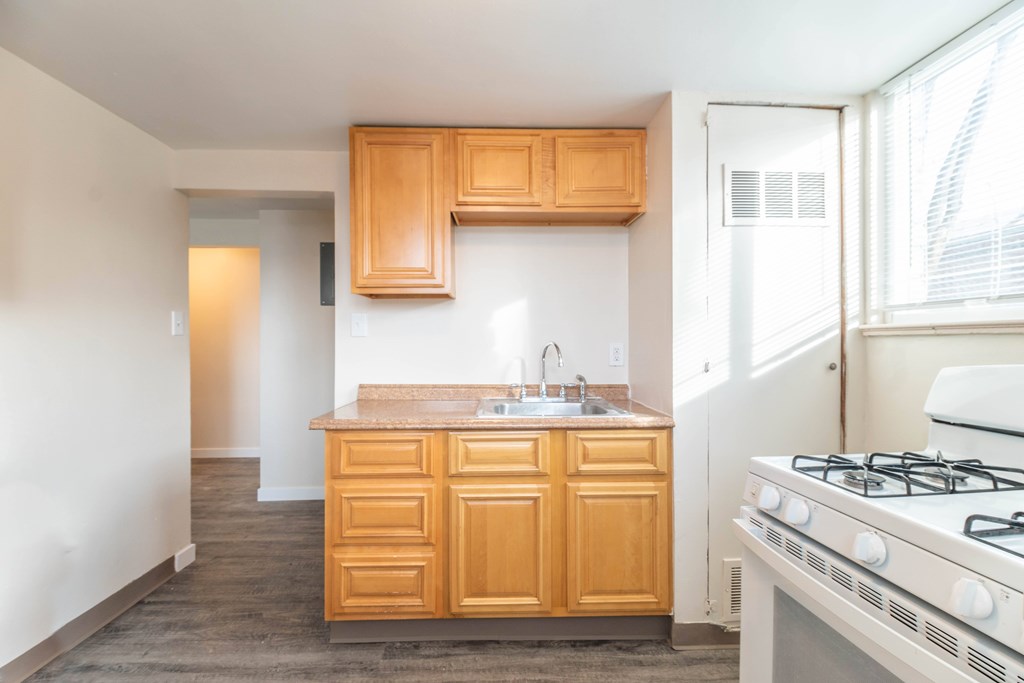 A kitchen with a white stove and wooden cabinets.