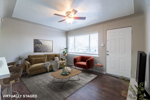 A living room with a brown couch, a red chair, and a coffee table.