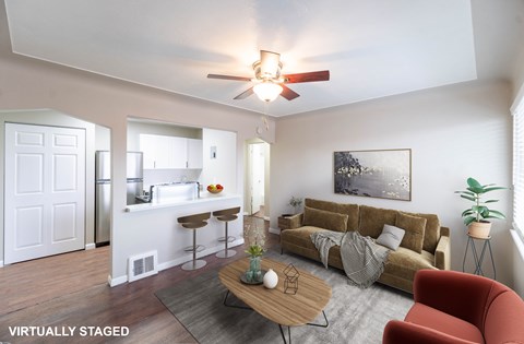 A living room with a couch, a table, and a ceiling fan.