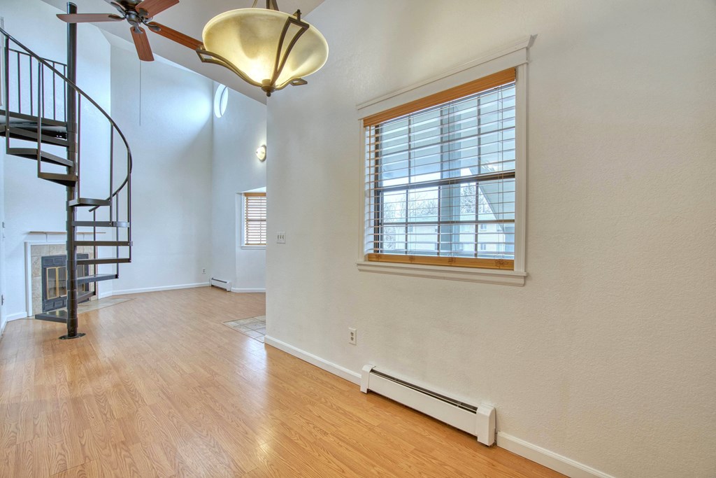 a living room with hardwood floors and a spiral staircase
